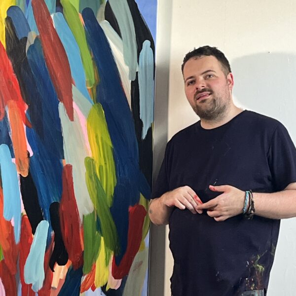 Chris stands next to on of his large paintings.
