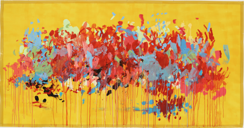 A large abstract painting with a bright yellow background. reds, blues, oranges and pinks are dotted, spattered, and shipped with long drips marks running off the page at the bottom.