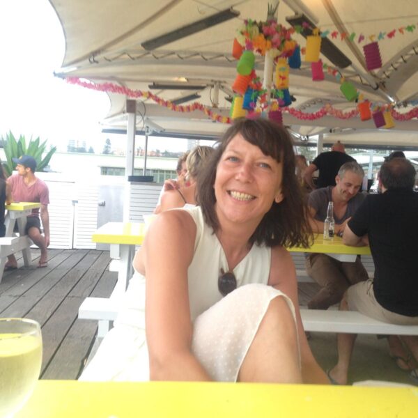 Gaby has short bobbed brown hair and is wearing a whit top. Gaby is smiling at the camera.